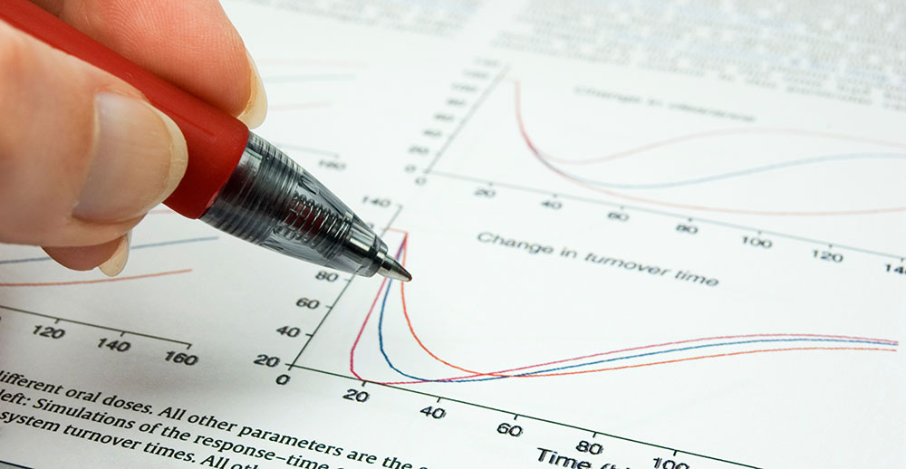 Hand holding pen poised above a chart on paper
