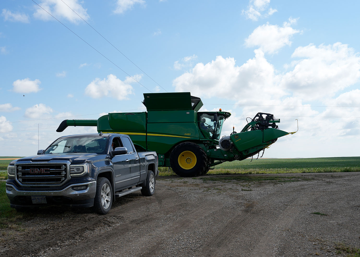 Truck parked on side of road with large farm equipment behind it