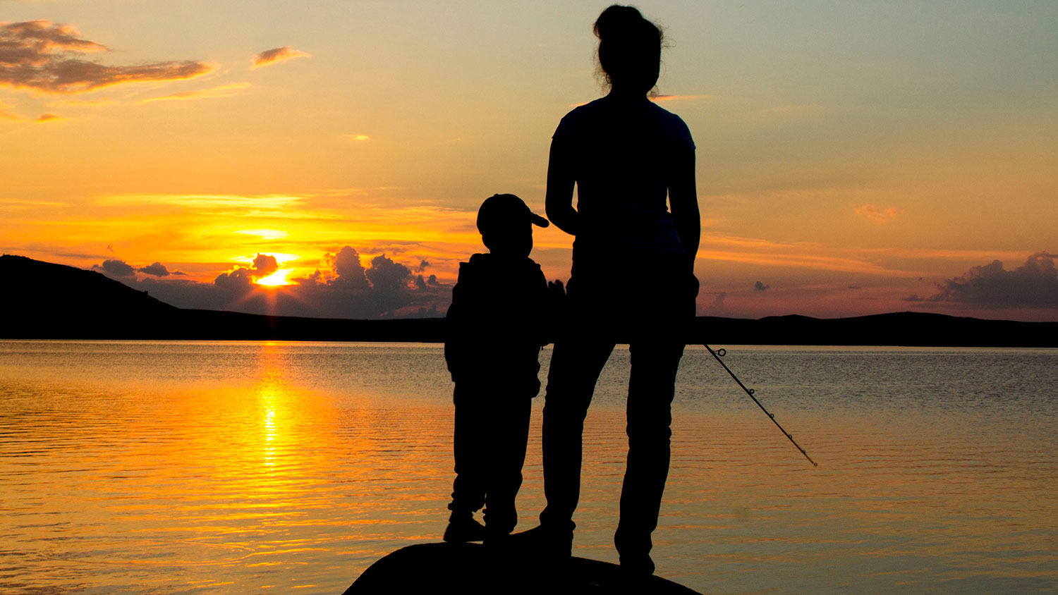 Woman and child fishing on lake