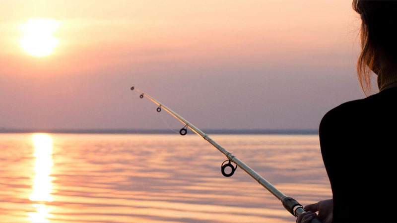 Woman fishing at sunset