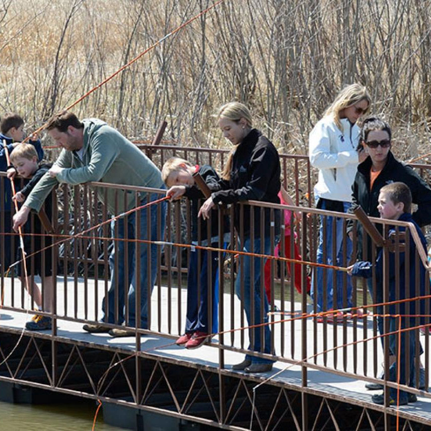 Families fishing off dock at pond