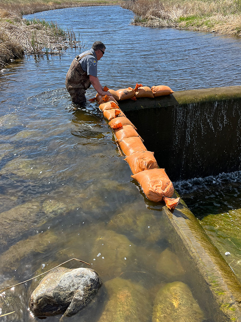 Warden putting sandbags on the spillway to redirect water