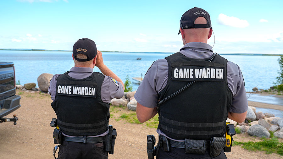Two game wardens looking out over the water