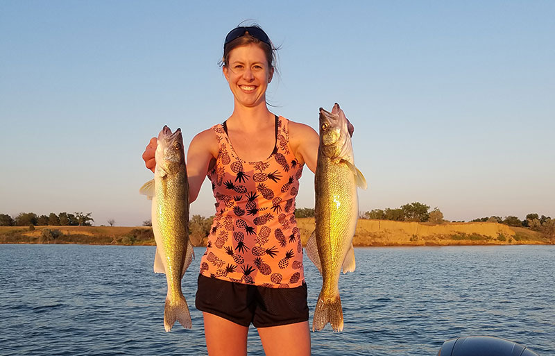 Woman on boat holding two walleye