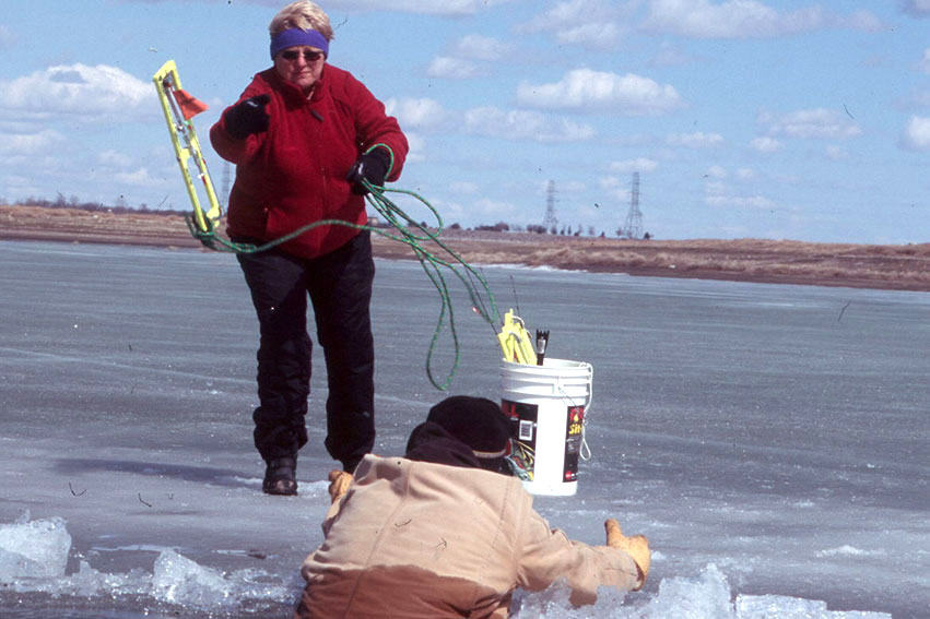 Woman throwing roap to man who fell throught the ice