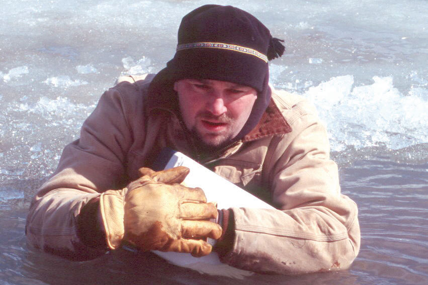 Man in water holding empty jug to stay afloat