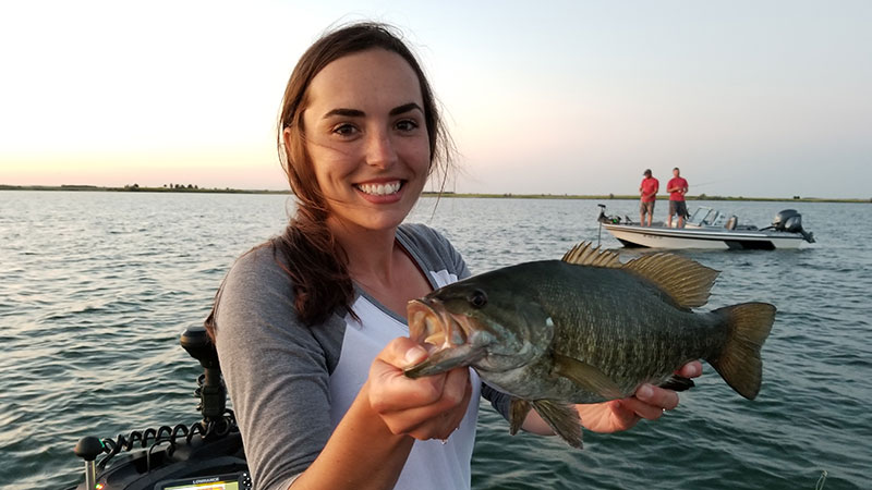 Angler on boat holding a fish she caught