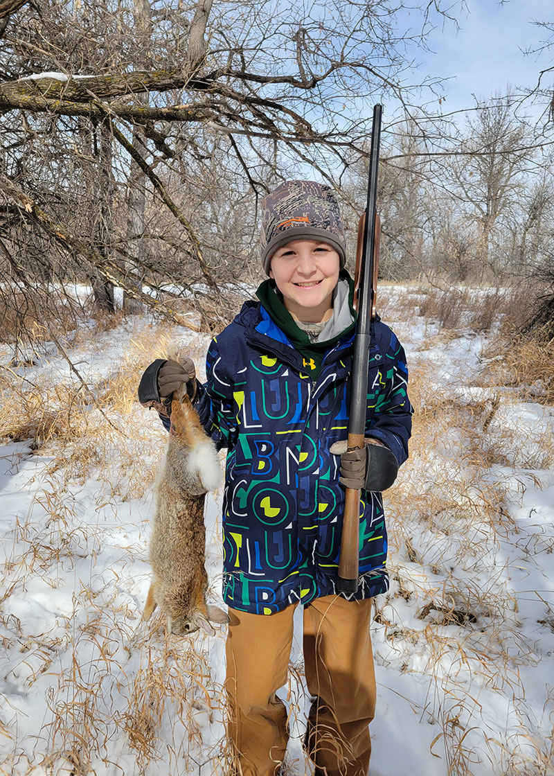 Youth with gun and harvested rabbit