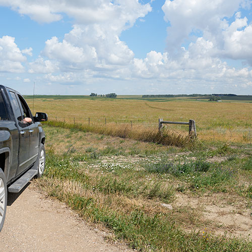 Truck parked on gravel near an unposted field