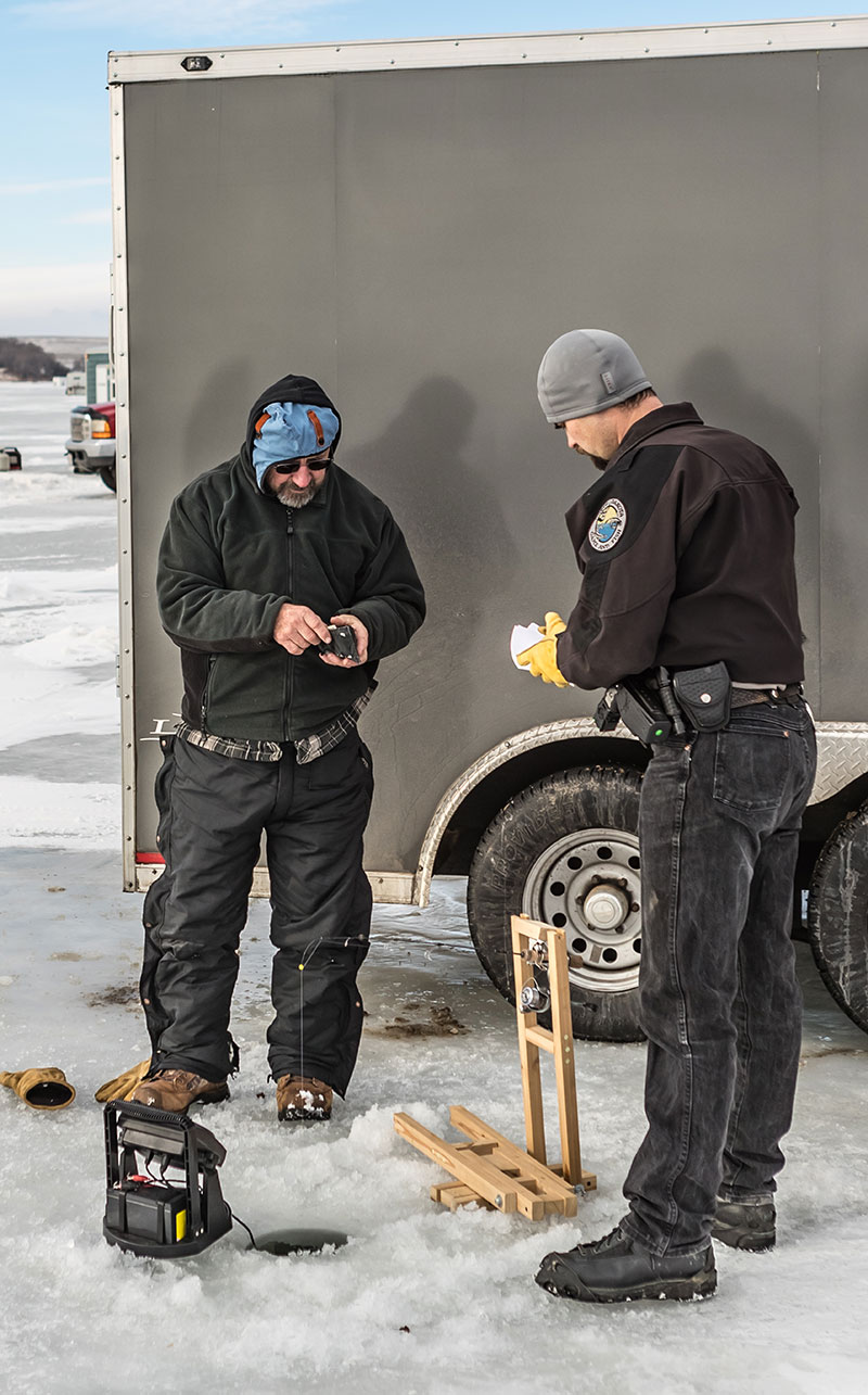 Game warden checking an ice angler's licensing