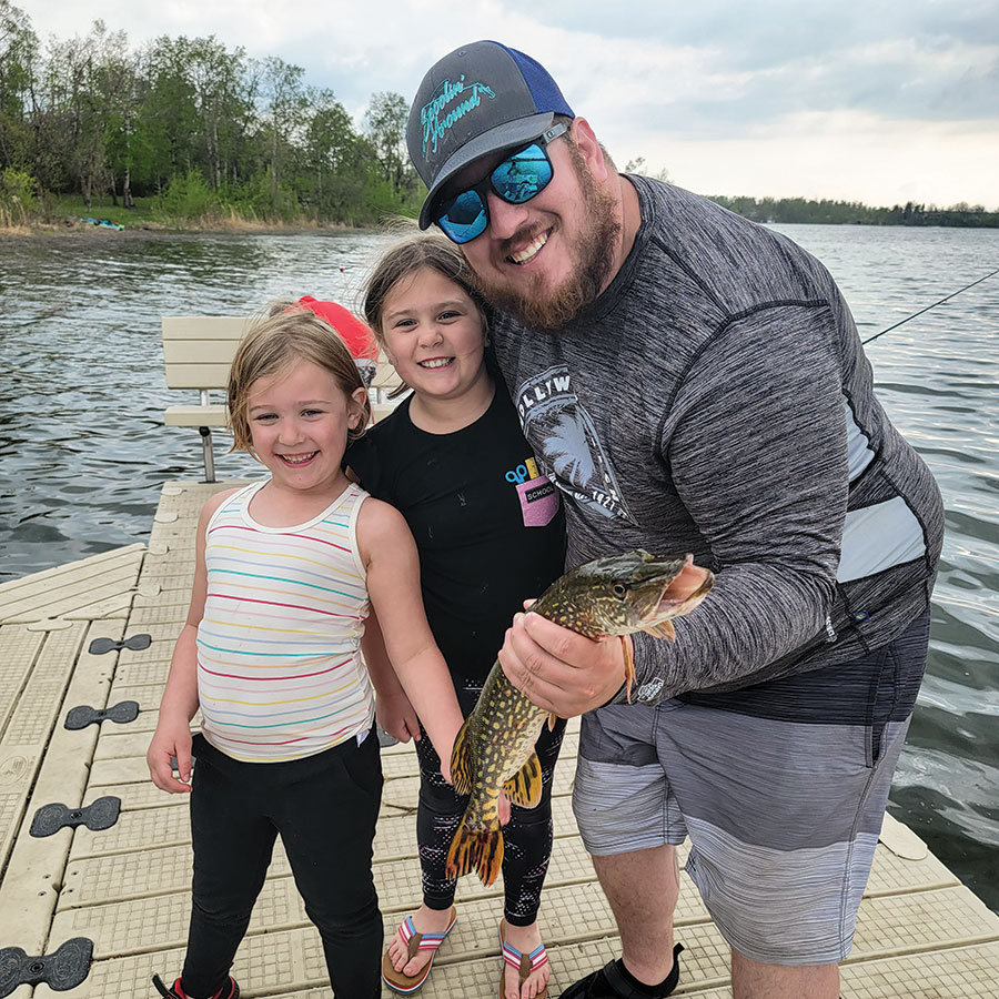 Man with two girls holding pike he caught shore fishing