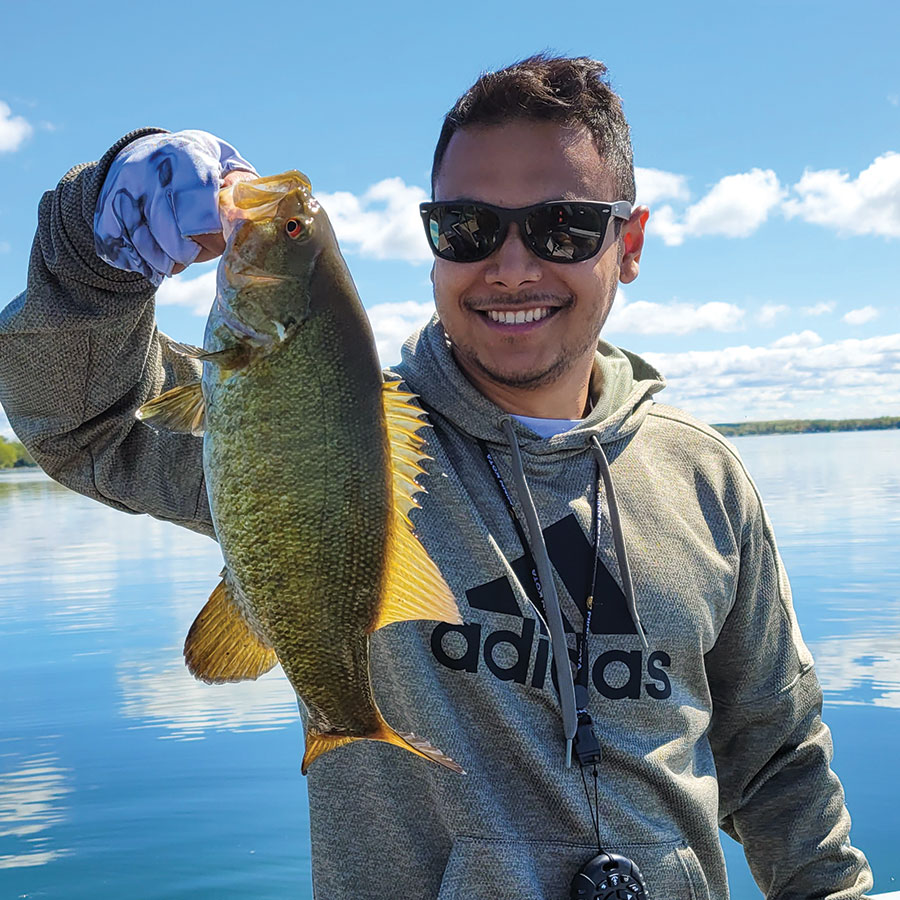 Man holding smallmouth bass he caught boating