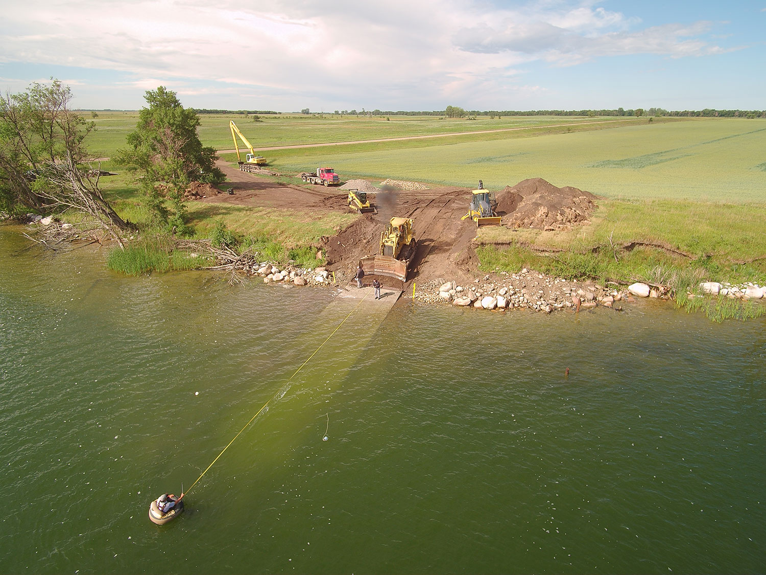 Aerial view of workers building a boat ramp. One worker is in the water measuring.
