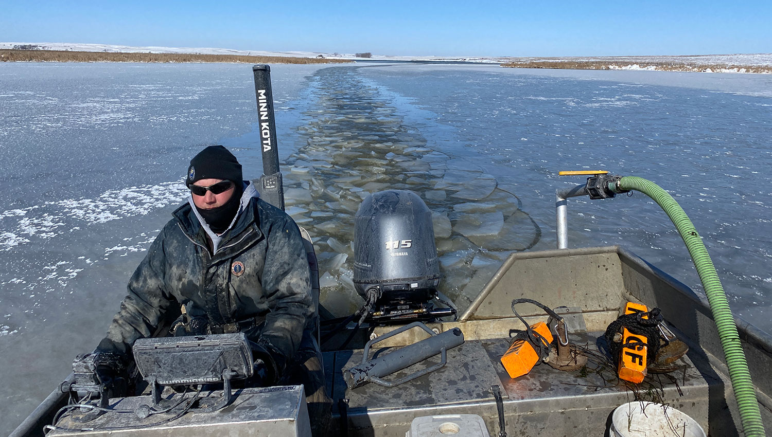 Fisheries biologist driving boat through thin ice