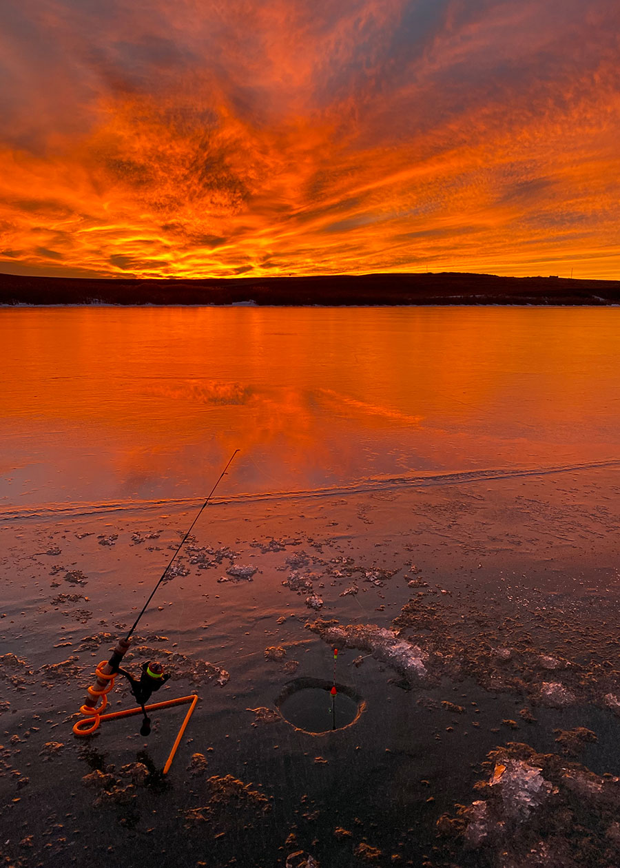 Ice fishing pole and hole at sunset