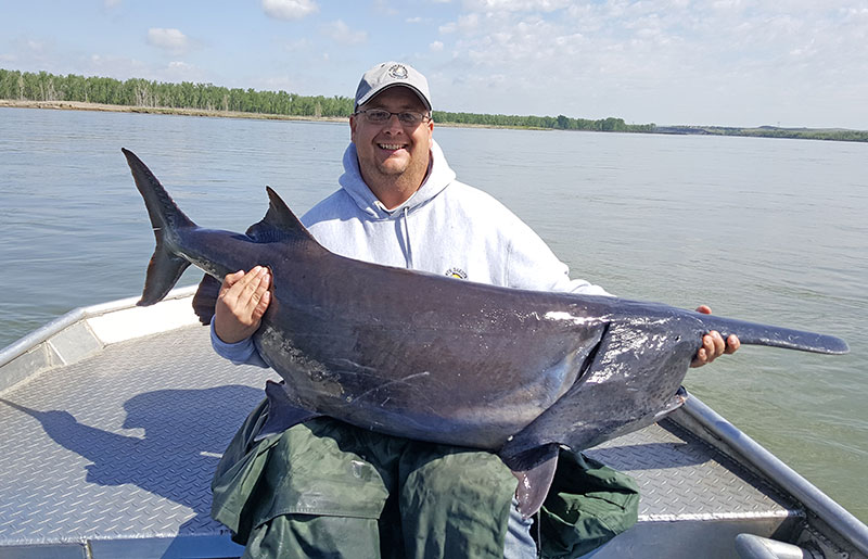 Mike Anderson on boat holding large paddlefish