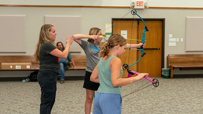 Teacher working with students doing archery