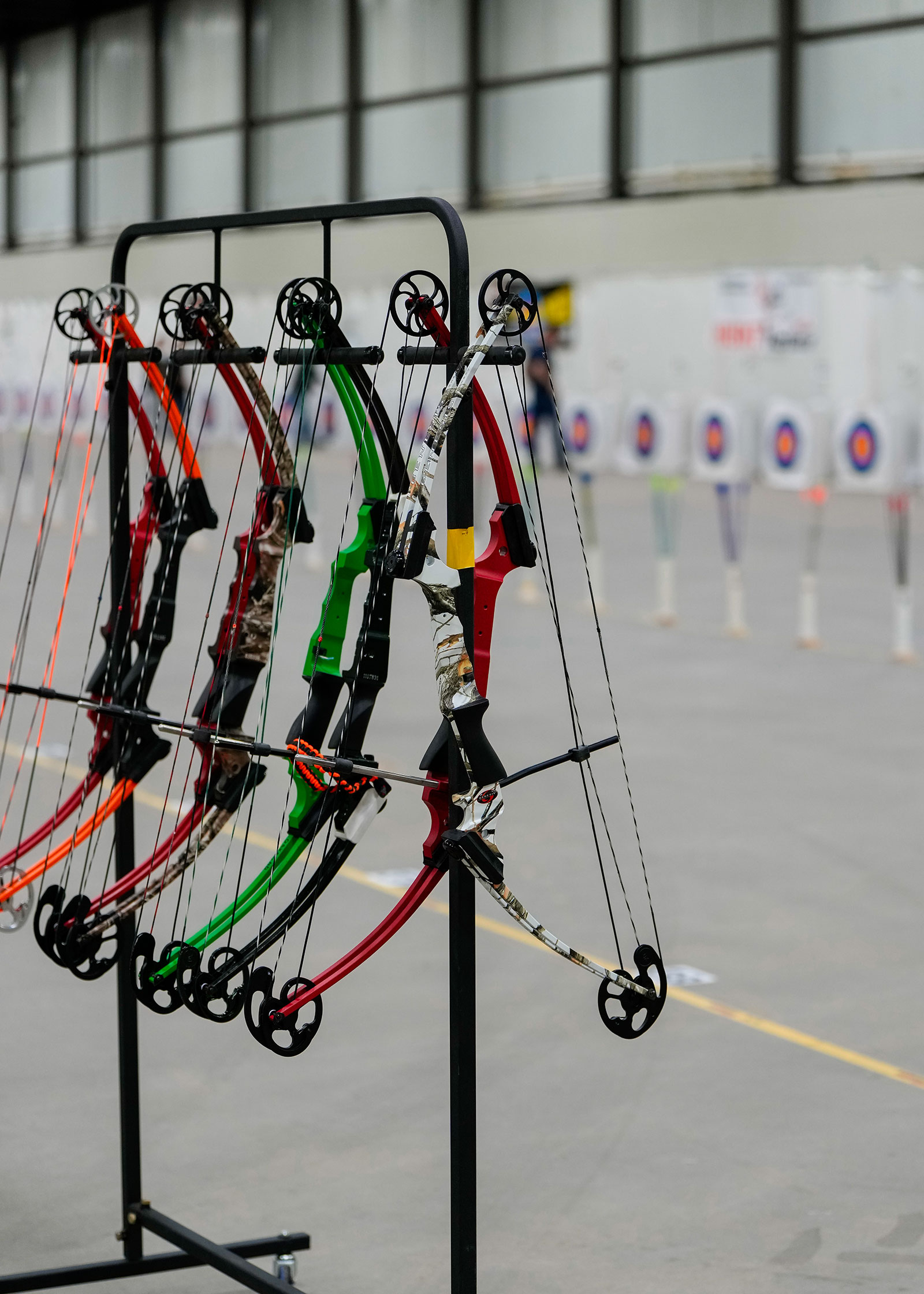 NASP bows hanging from a rack with targets visible behind