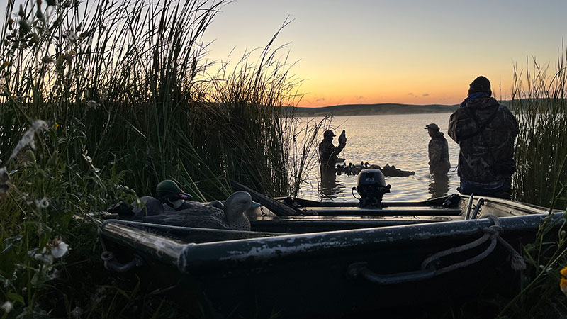 Duck hunters near boat setting out decoys