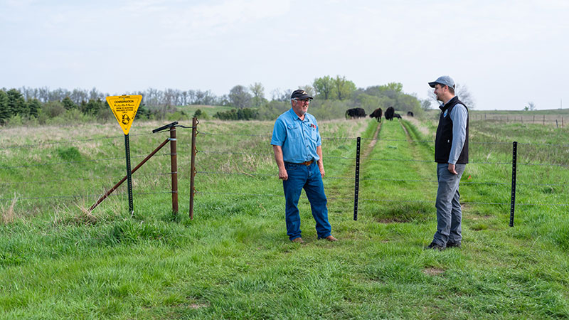 Staff member and landowner talking with cows in background