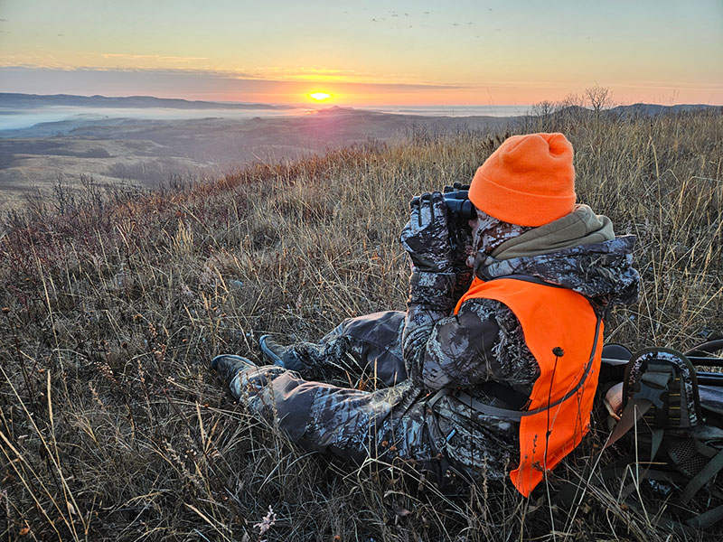 Hunter on a hill with sun coming up