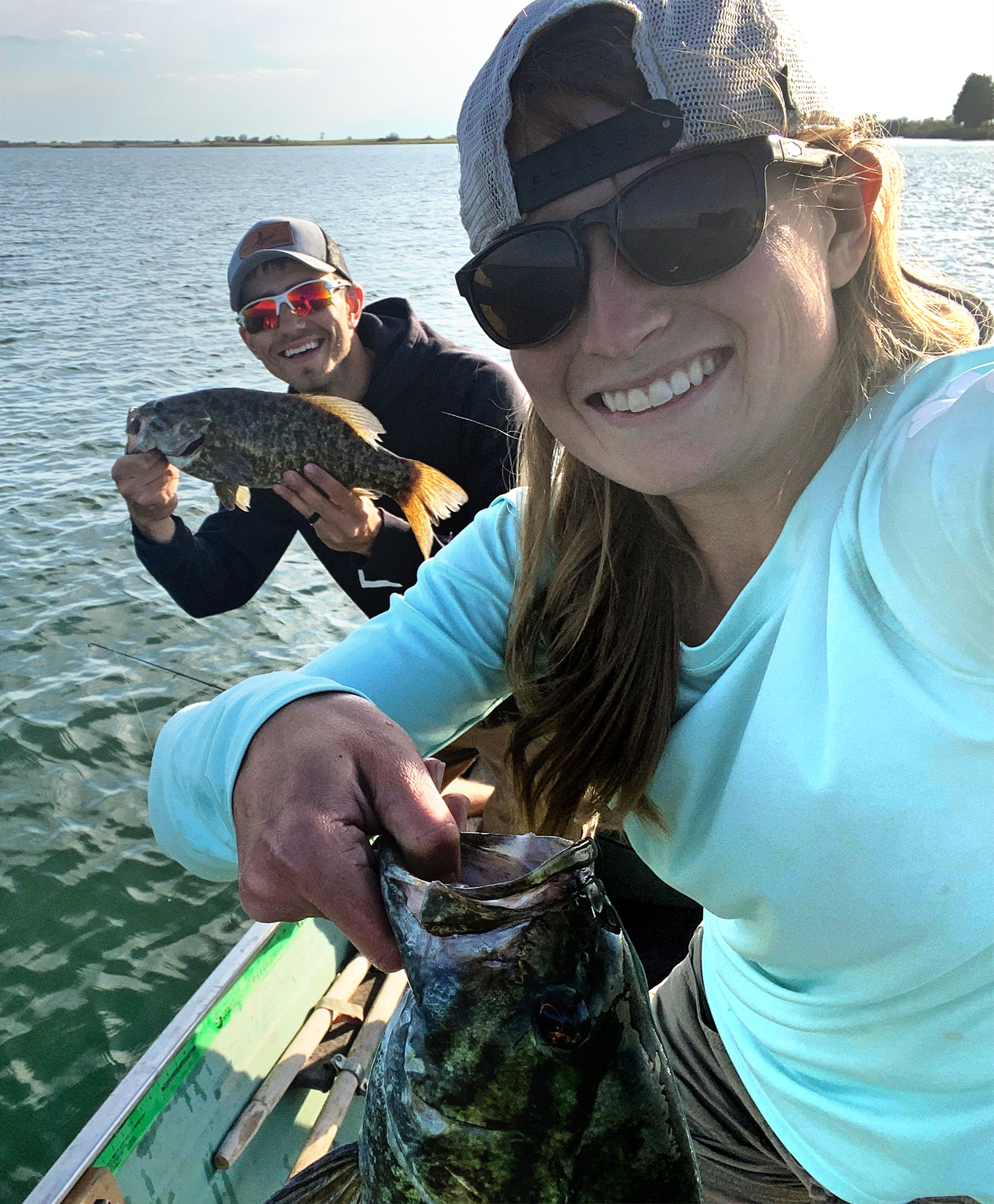 Cayla and her husband on their boat holding fish they caught