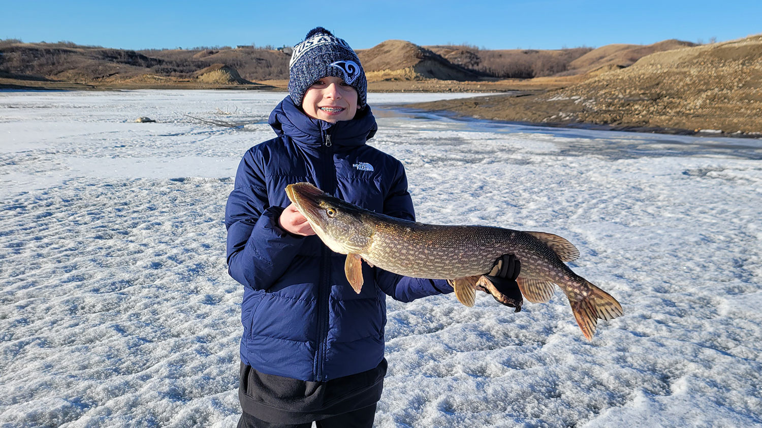 Kid holding pike he caught ice fishing