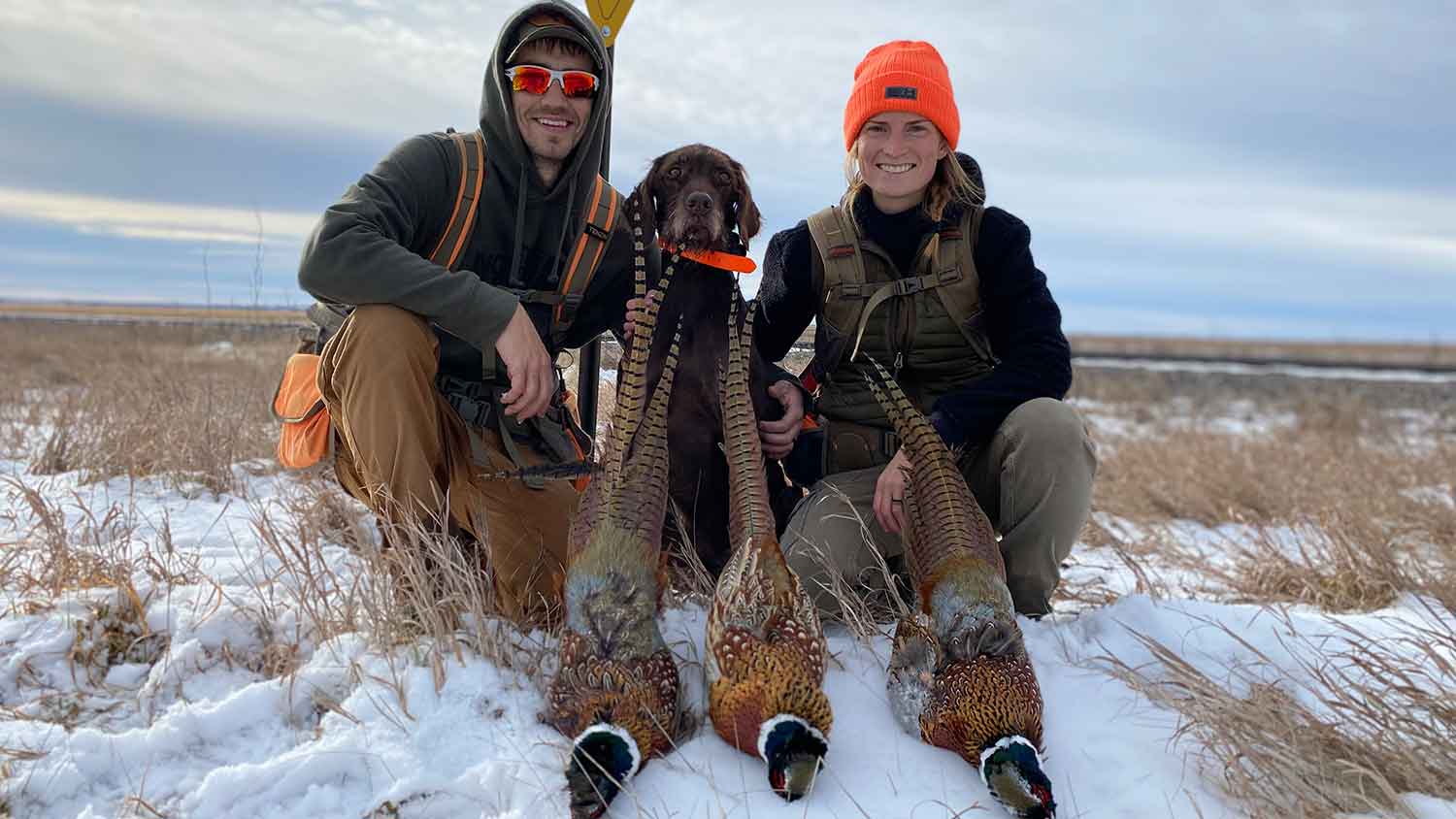 Cayla and her husband and Fin with harvested pheasants