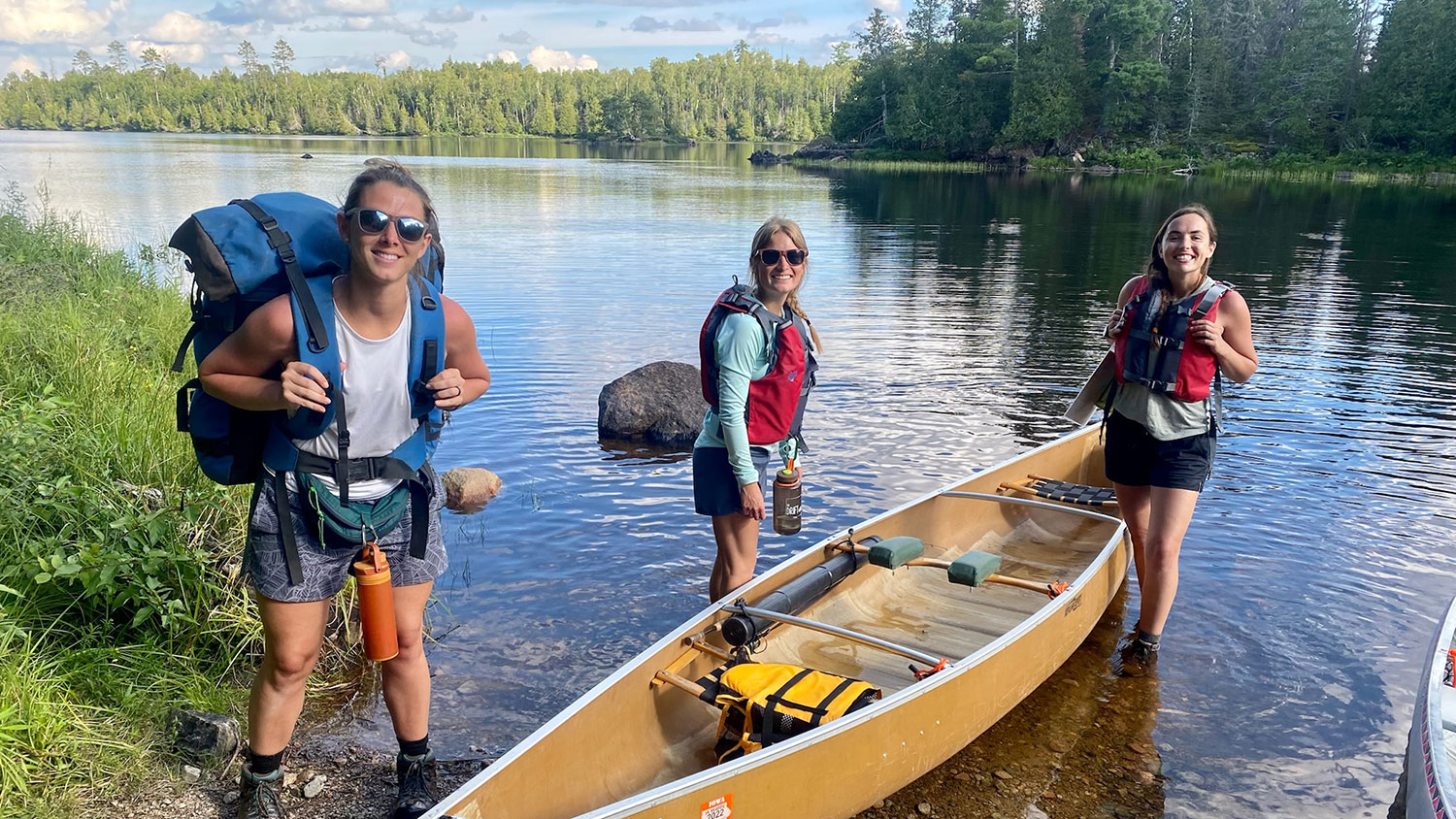 3 Woman near canoe in water at the start of a trip