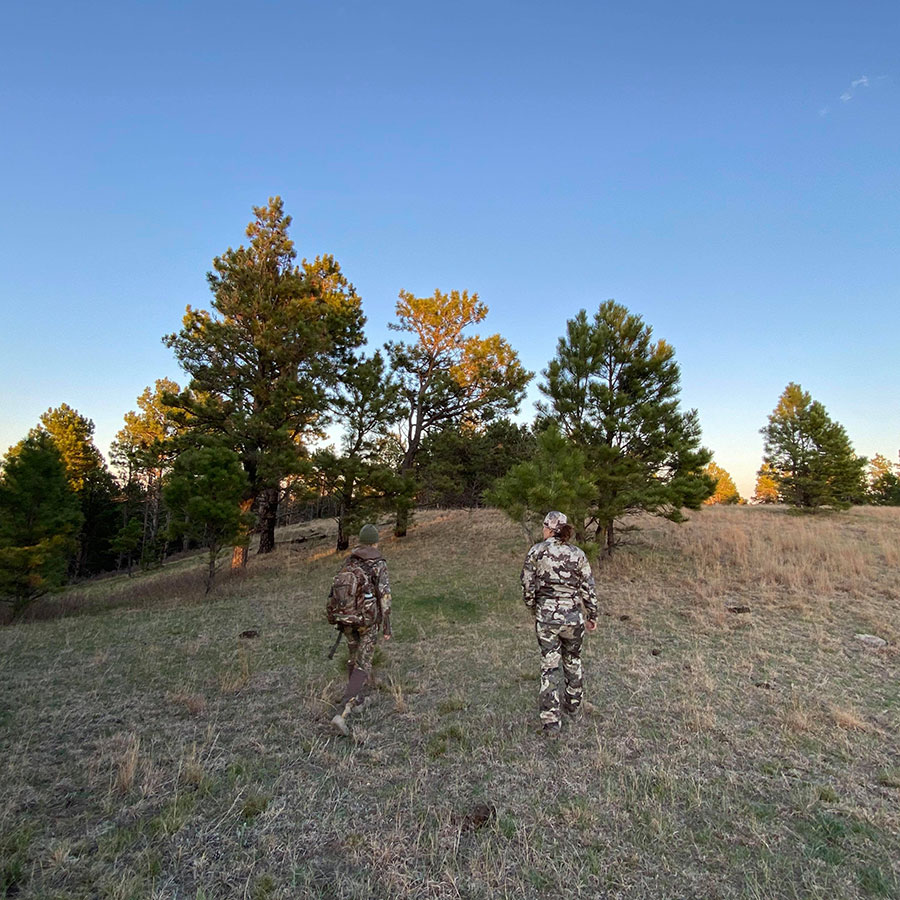 Two hunters walking in a field in the fall