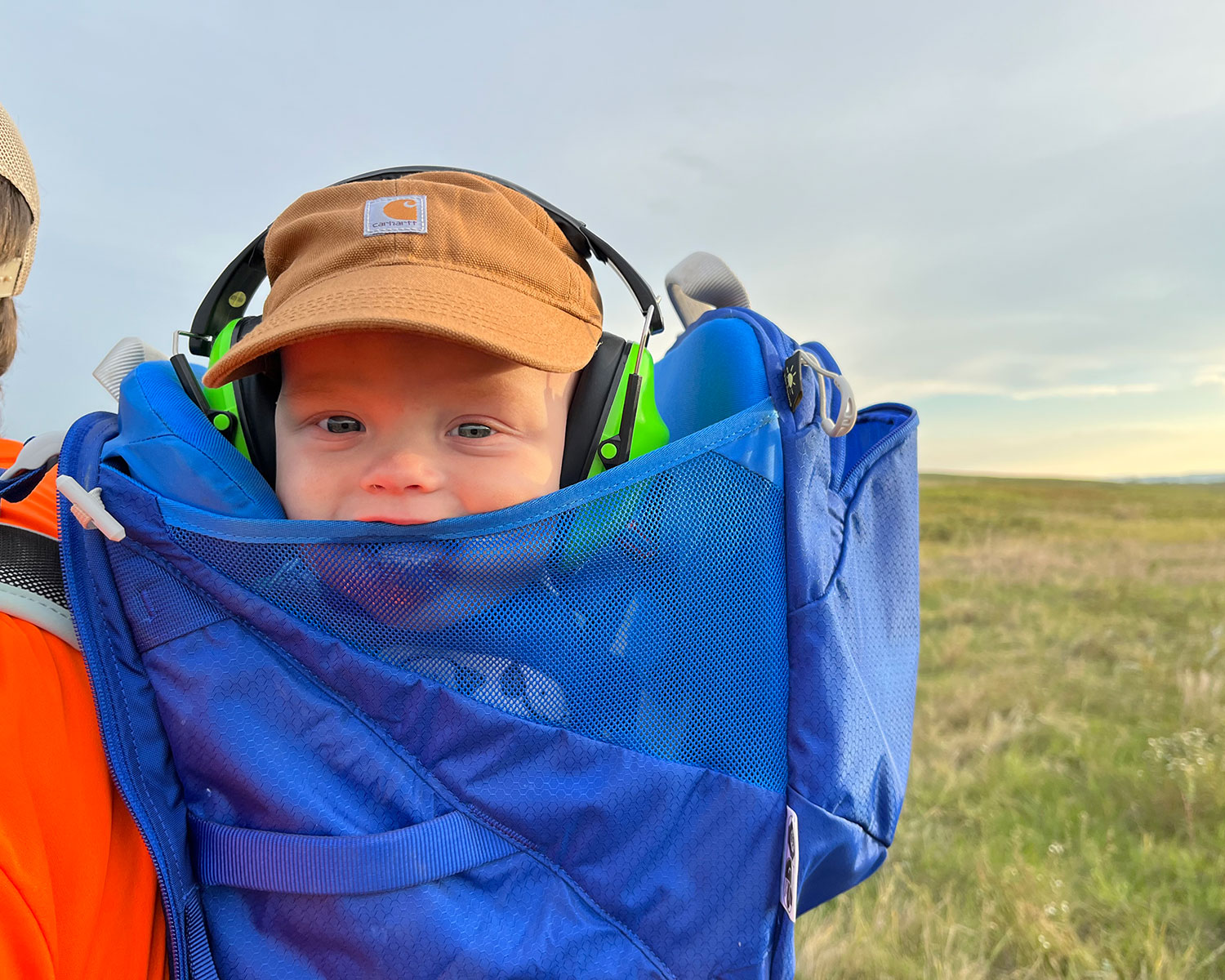 Fisher in backpack with prairie in background