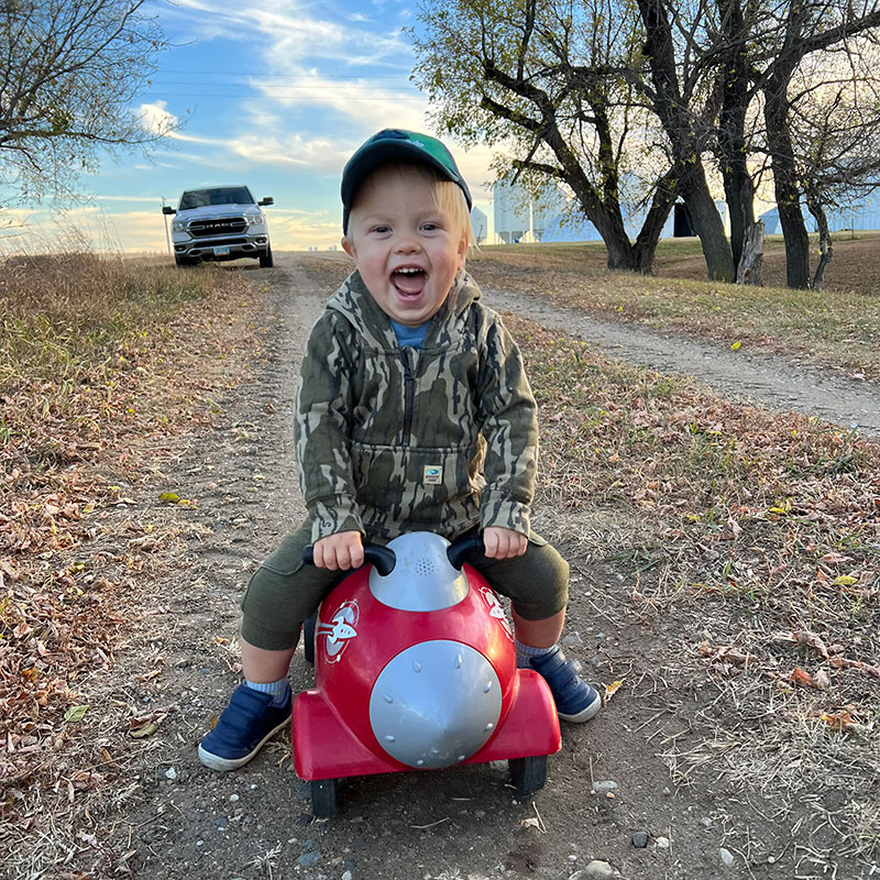 Son playing on retro rocket toy on dirt road