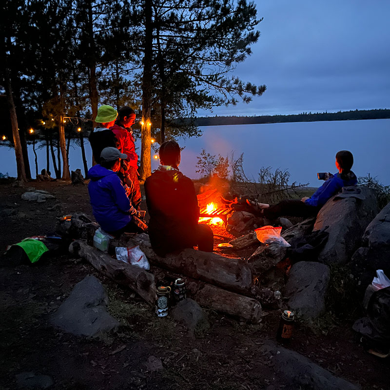 Group of friends at a campfire along a river