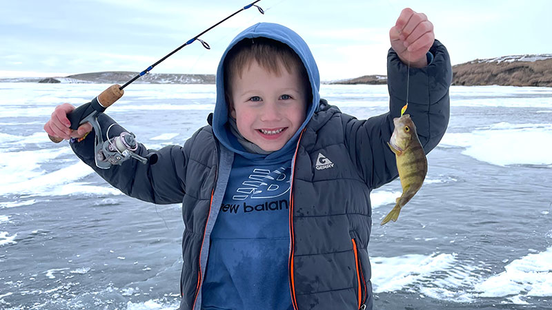 Kid showing off fish he caught ice fishing