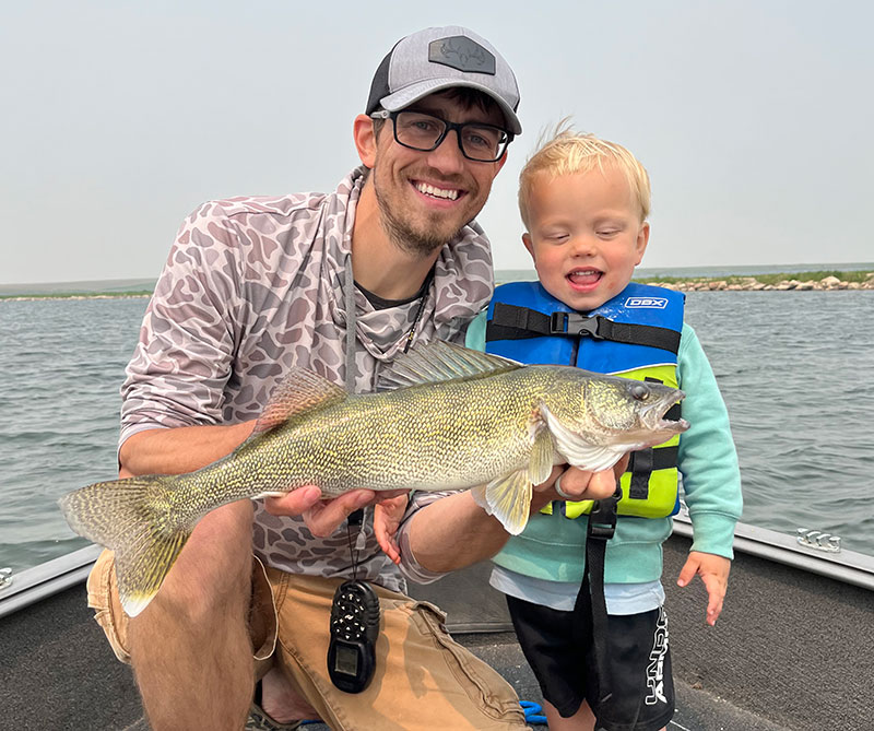 Man and son on boat holding fish they caught