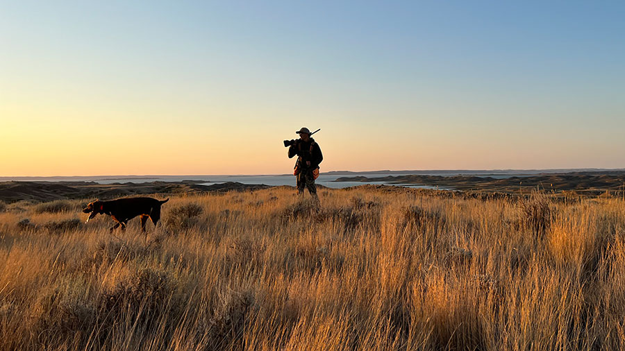 Man and dog in field hunting with water behind