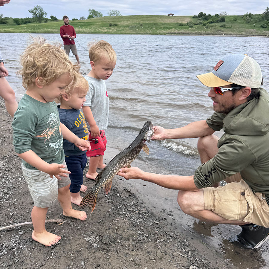 Angler showing pike to kids