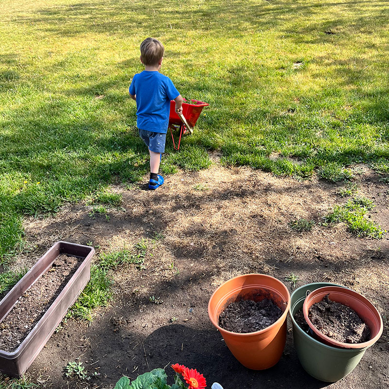Child pushing a wheeled barrel