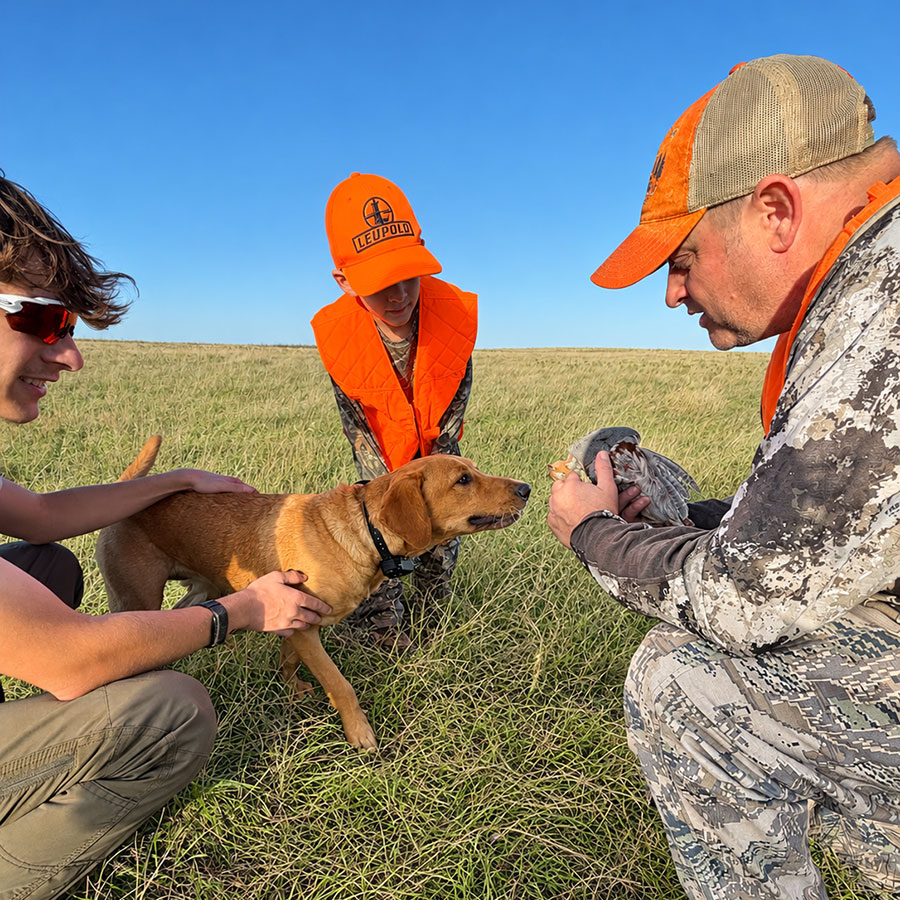 Hunters and dog looking at harvested bird