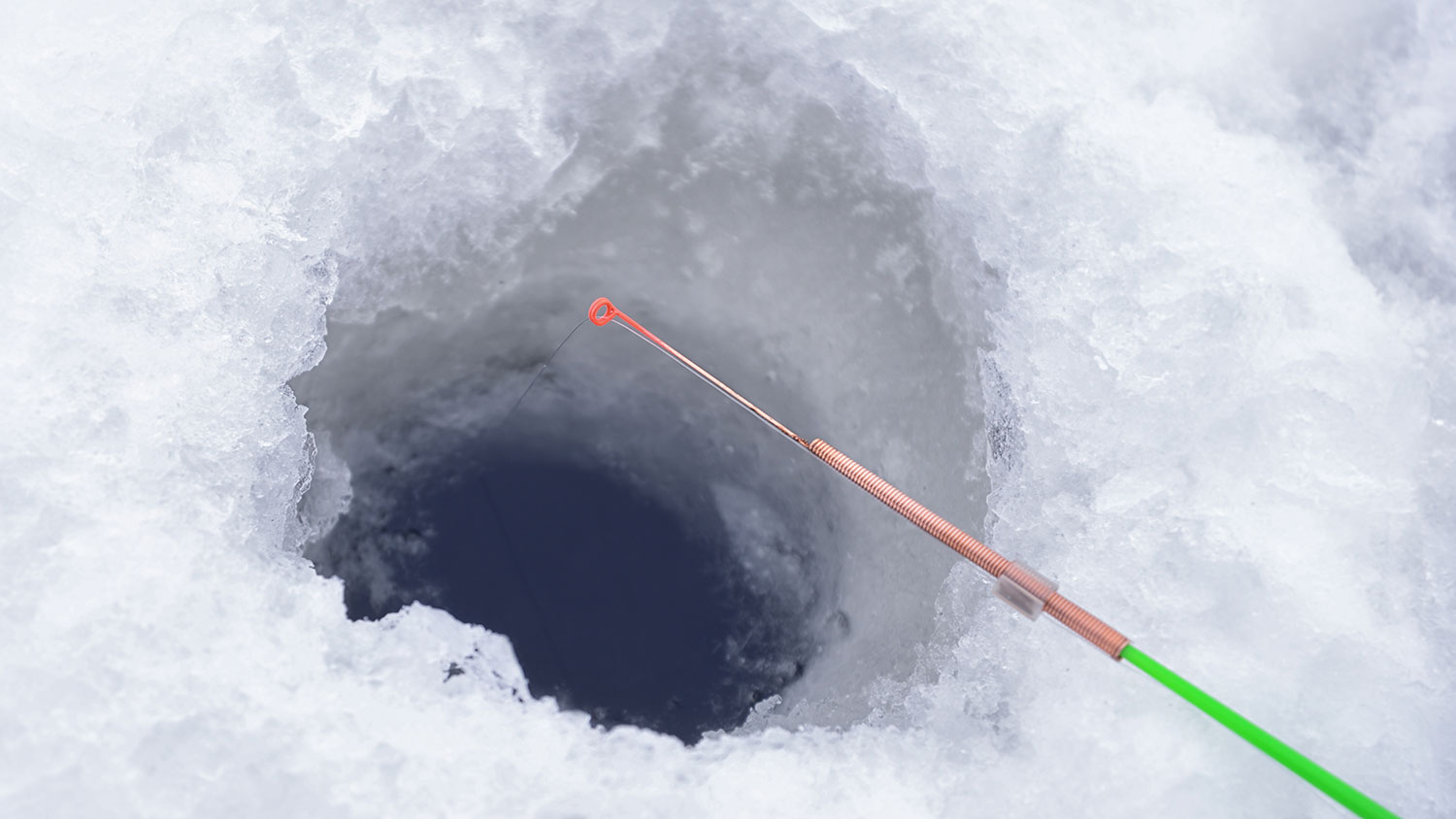 Ice fishing pole and line at ice hole