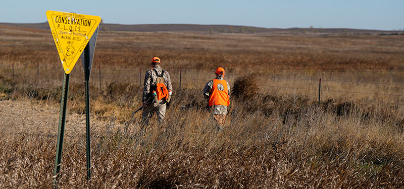 Hunters walking behind PLOTS signs