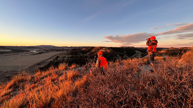 Hunters on a prairie hill looking for deer