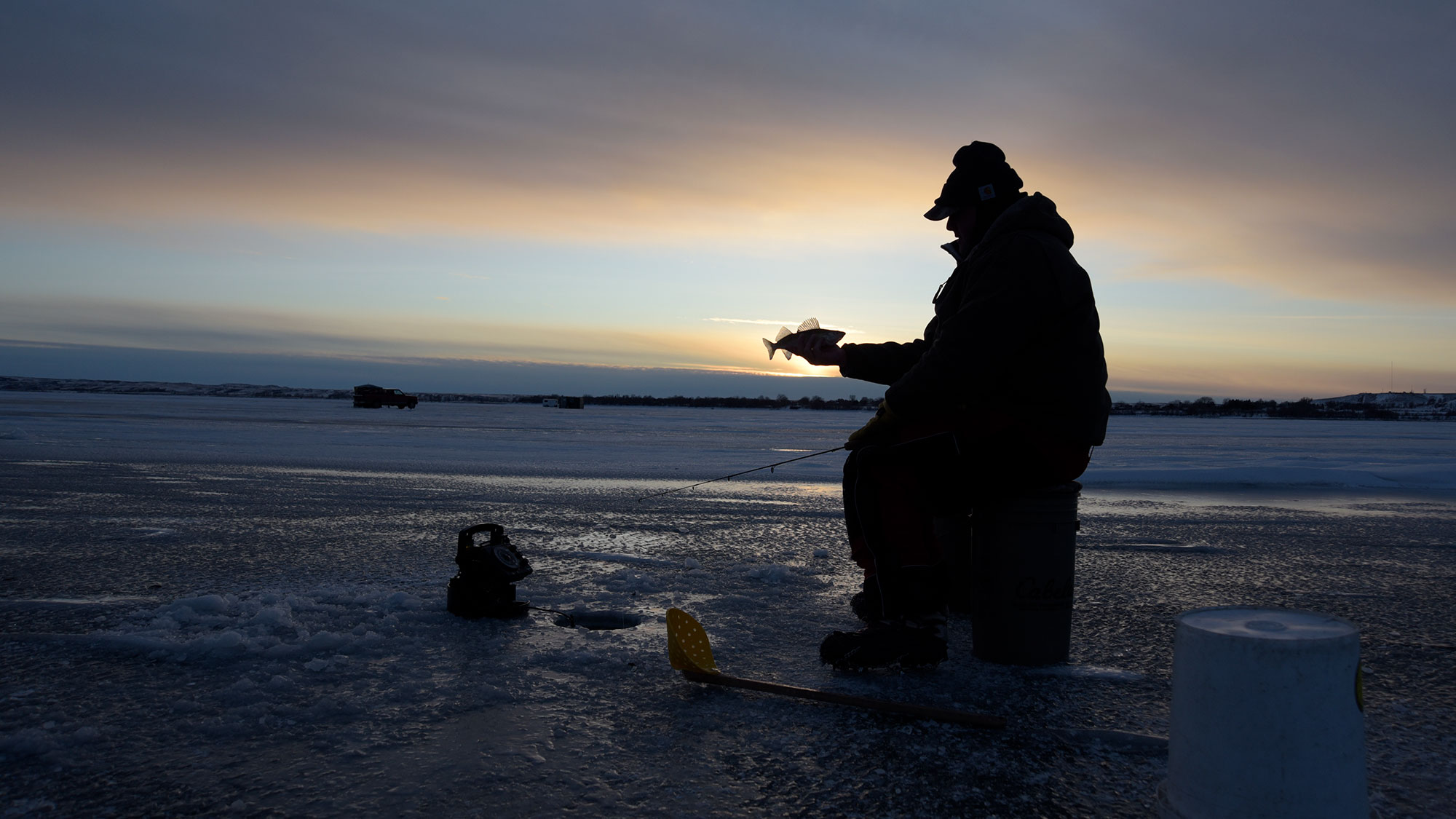 Angler sitting on a bucket ice fishing