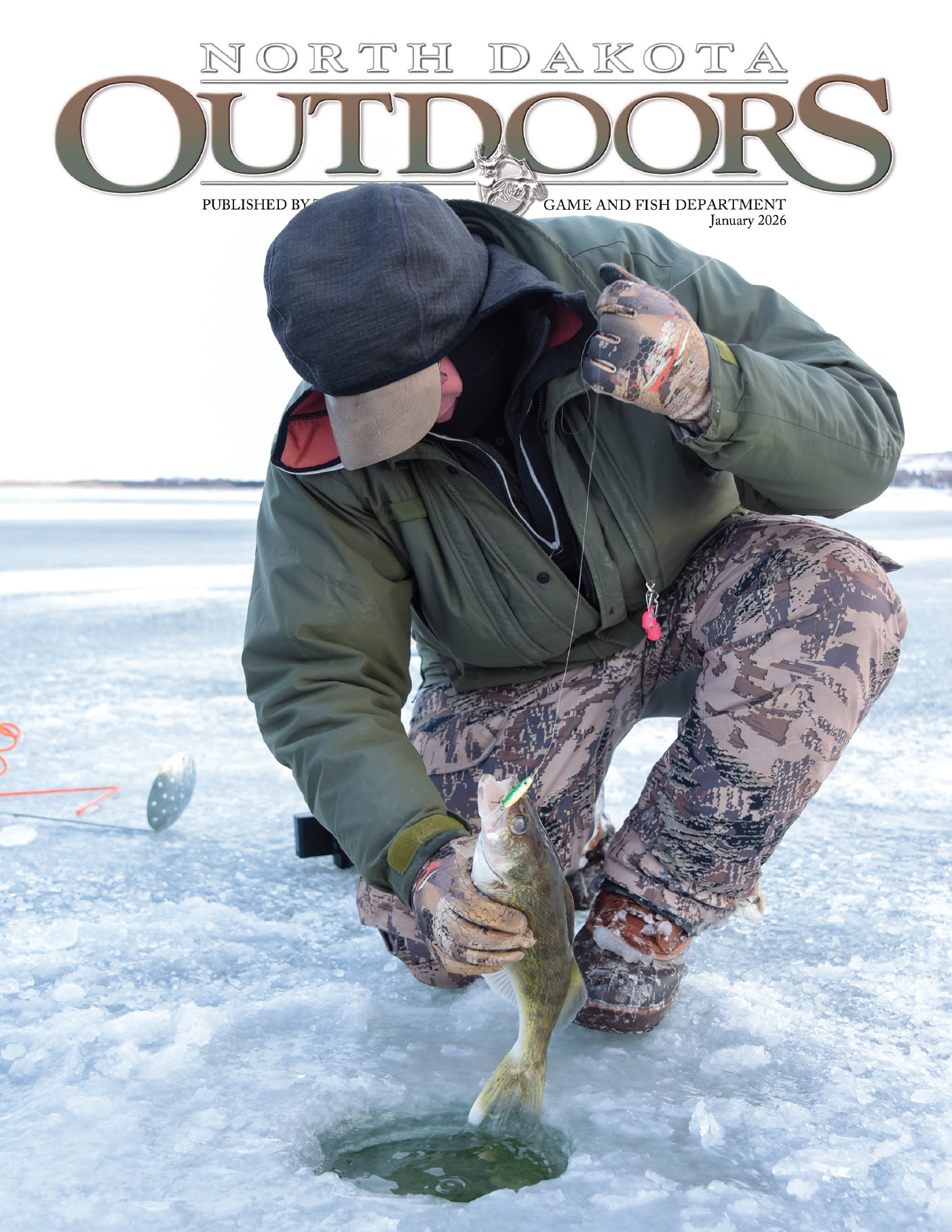 Cover of the magazine - Person pulling fish out of an ice fishing hole