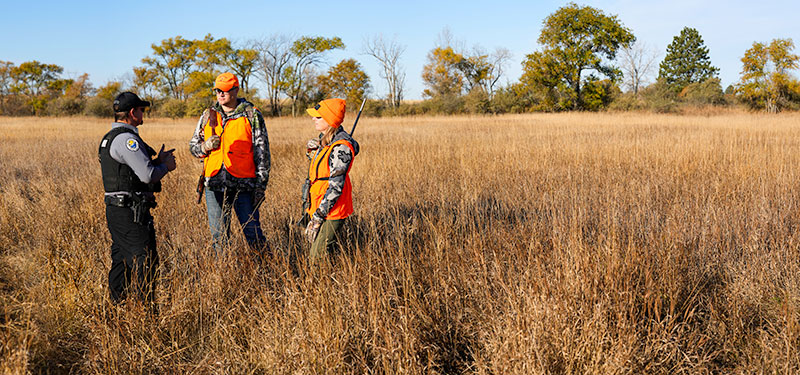 Warden talking to hunters in the field