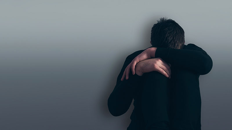 Depressed boy sitting against a wall