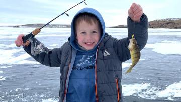 Kid with fish he caught ice fishing