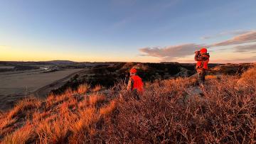 Hunters on a prairie hill looking for deer