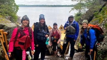 Group of women with canoes by river