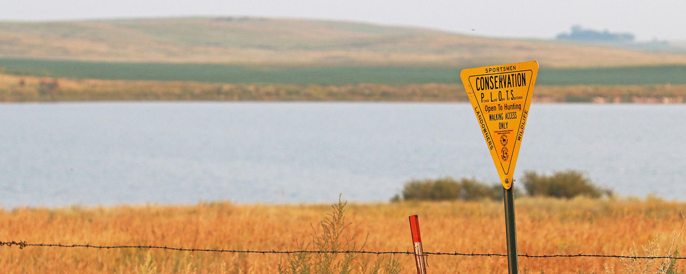 PLOTS Sign by water